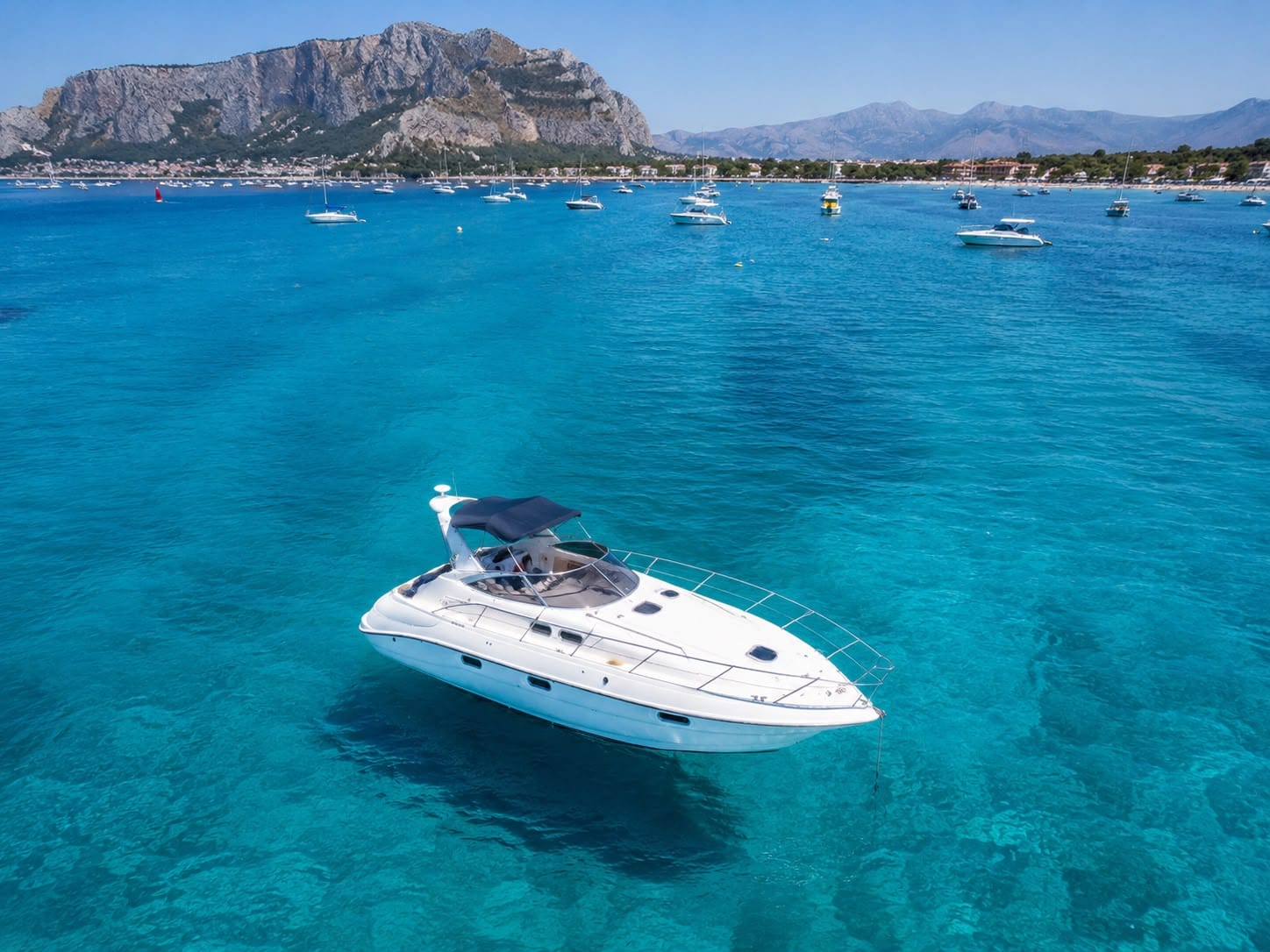 Sealine S34 yacht anchored in the turquoise water of Mondello bay with Monte Gallo behind